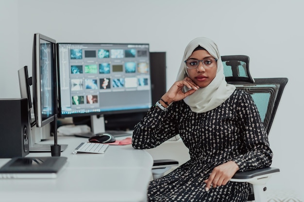 Young Afro-American modern Muslim businesswoman wearing a scarf in a creative bright office workplace with a big screen. High-quality photo