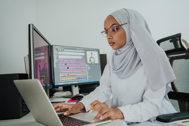 Young Afro-American modern Muslim businesswoman wearing a scarf in a creative bright office workplace with a big screen. High-quality photo