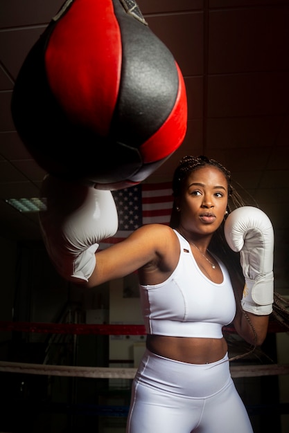 Young afro american woman training boxing in gym with the United States flag