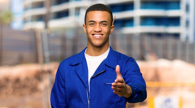 Young afro american worker man shaking hands for closing a good deal in a construction site