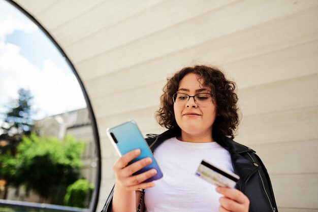 ビジネスオンラインショッピングのためにスマートフォンを使用している若いアフロ美しい女性送金金融インターネットバンキング