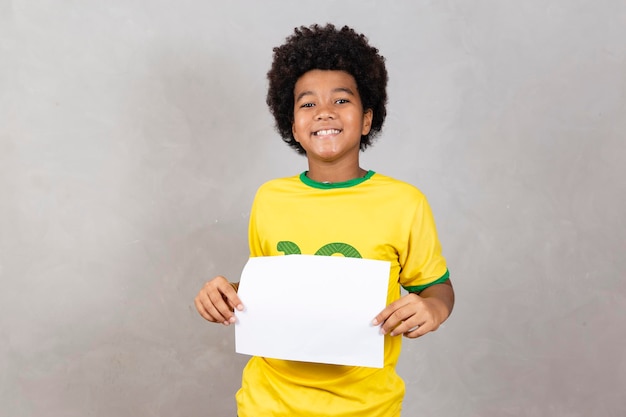 Young afro boy brazilian fan holding blank board with copy space