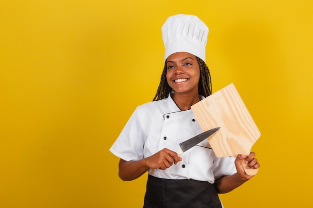 Young afro brazilian woman chef cook holding wooden board and knife