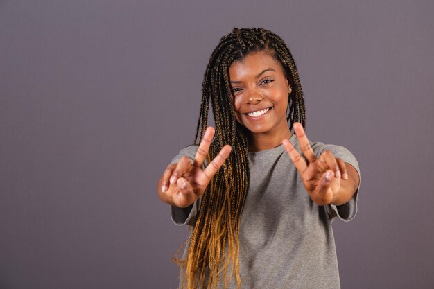 Young afro brazilian woman hands forward fingers in peace and\
love wishing you good vibes