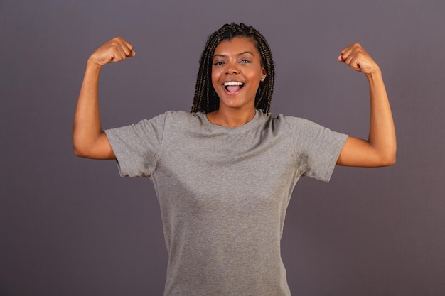 Young afro brazilian woman showing both biceps sign of strength