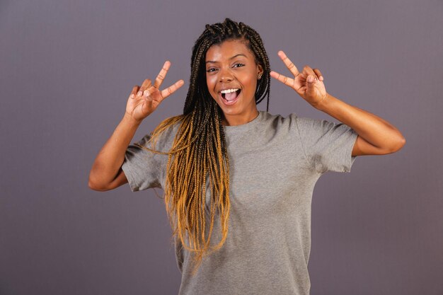 Young afro brazilian woman with peace and love sign with fingers happy joyful