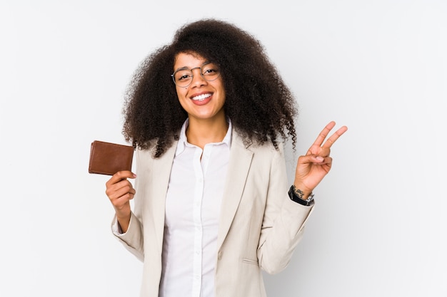 Young afro business woman holding a credit car isolated Young afro business woman holding a credit carjoyful and carefree showing a peace symbol with fingers.