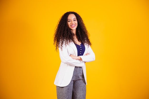 Young afro business woman with arms crossed on yellow background