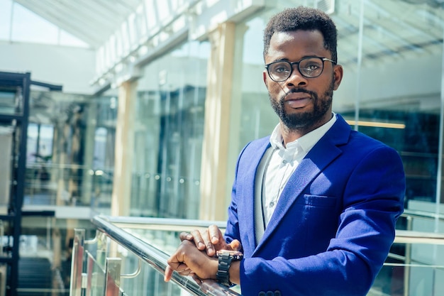 Photo young afro businessman in blue suit stands in office looks through big window at the city in airport terminal l .