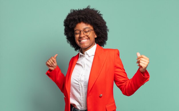 Young afro businesswoman against green wall