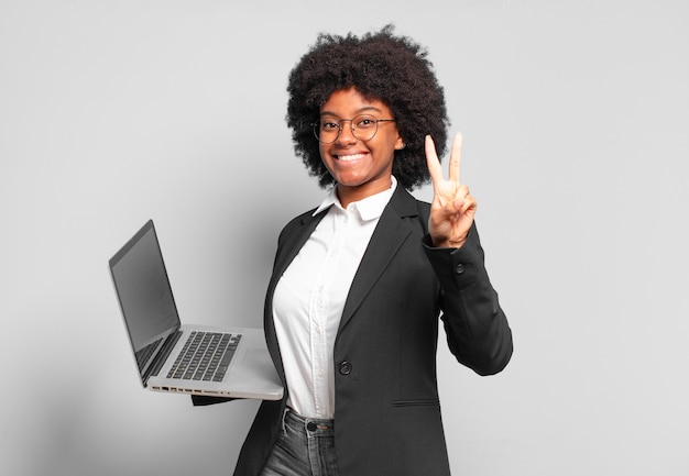 Young afro businesswoman smiling and looking friendly, showing number two or second with hand forward, counting down.