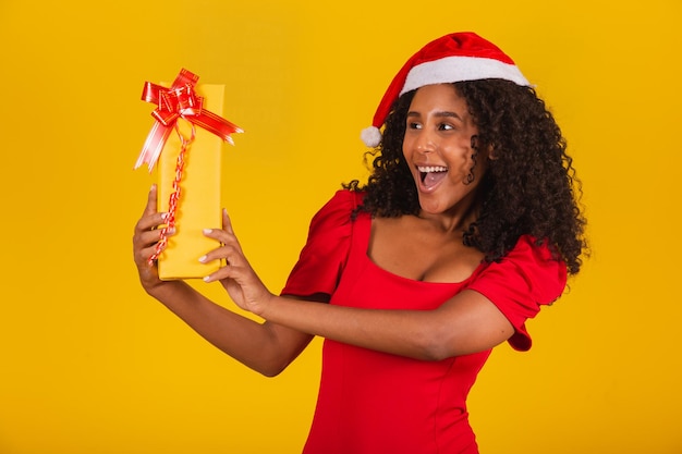 Giovane ragazza afro che tiene un regalo di natale espressivo.