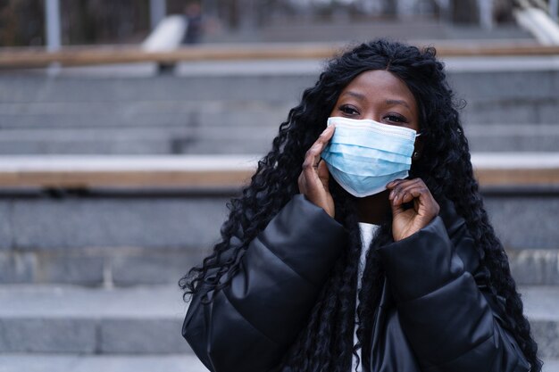 Young afro girl with face medical mask in a outdoors african girl using facemask