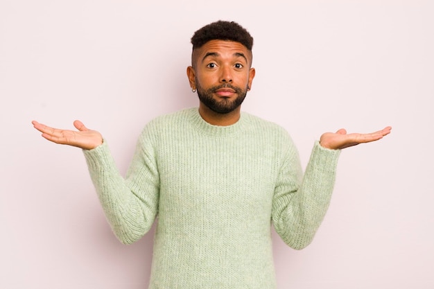 Photo young afro man feeling puzzled and confused doubting weighting or choosing different options with funny expression