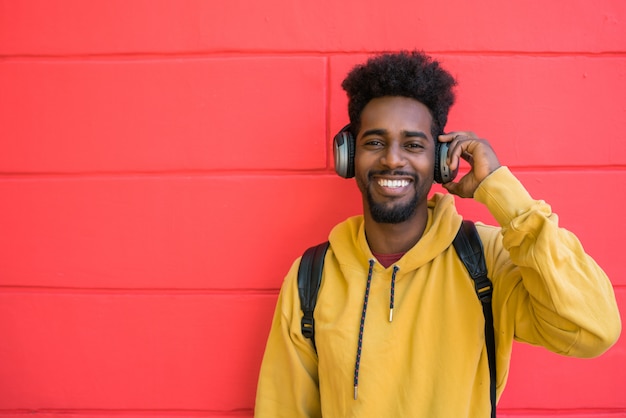 Young afro man listening to music with headphones.