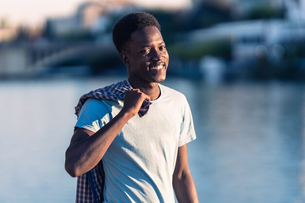 Young afro man with a shirt pulled over his shoulders facing the camera outdoors