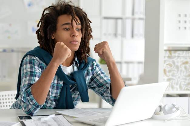 Photo young afro man working at office, using laptop