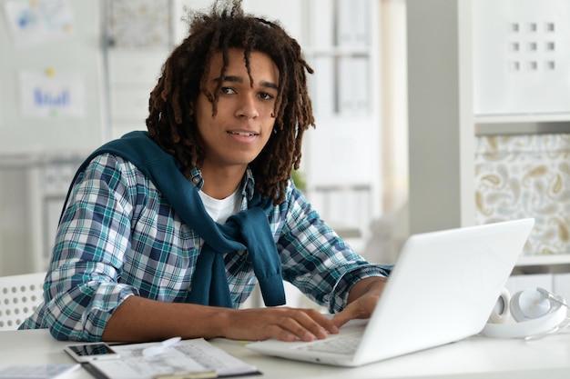 Молодой афро-человек, работающий в офисе, используя ноутбук