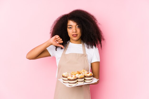 カップケーキを保持している若いアフロペストリーメーカーの女性