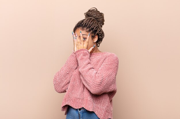 Young afro woman asking for silence and quiet, gesturing with finger in front of mouth, saying shh or keeping a secret