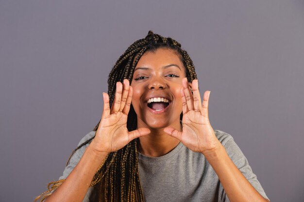 Young afro woman brazilian shouting with hands promotion
announcing discount called