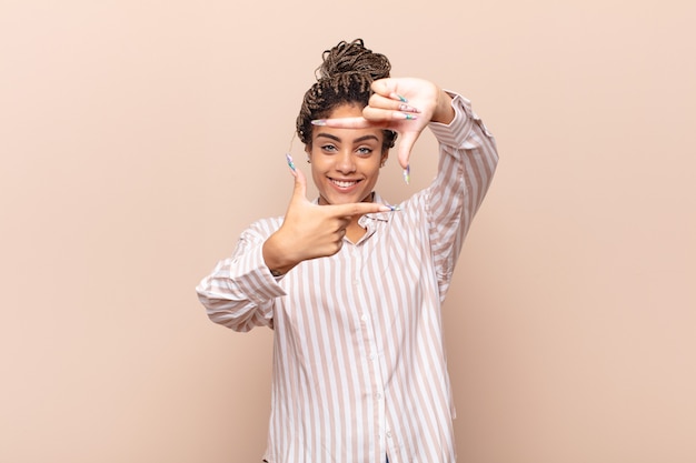 Young afro woman feeling happy, friendly and positive isolated