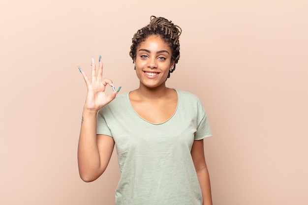 Giovane donna afro sentirsi felice, rilassata e soddisfatta, mostrando approvazione con un gesto ok, sorridendo