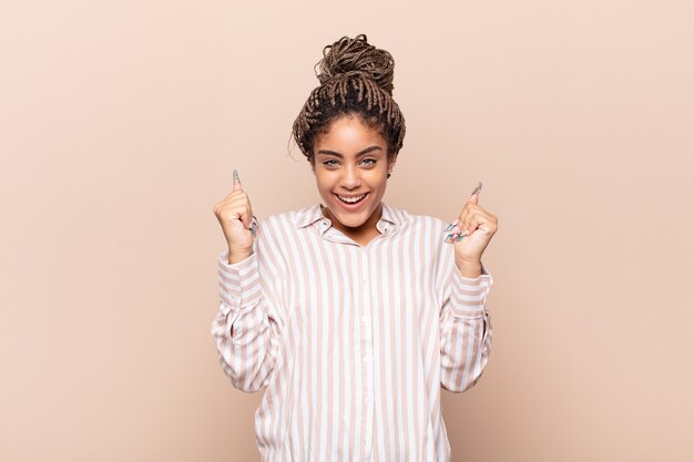 Young afro woman feeling happy, surprised and proud isolated