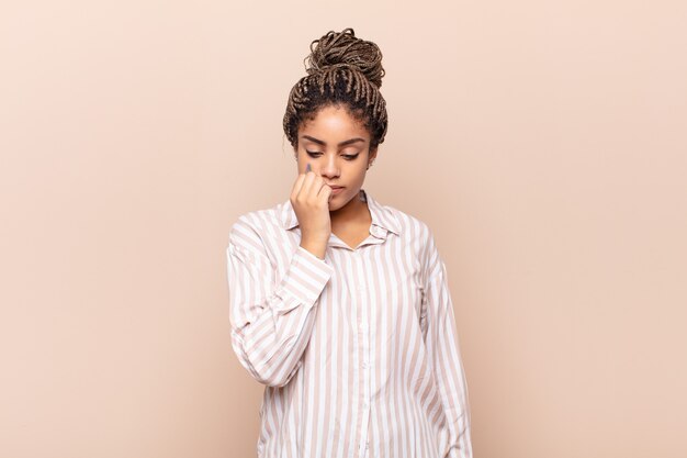 Young afro woman feeling serious, thoughtful and concerned, staring sideways with hand pressed against chin