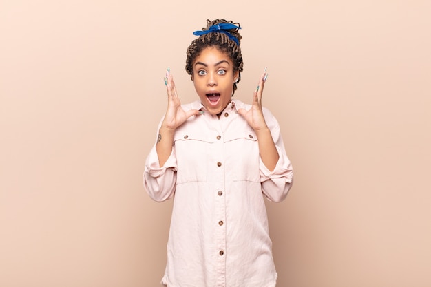 Young afro woman feeling shocked and excited, laughing, amazed and happy isolated