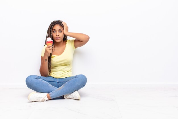 Young afro woman feeling stressed, worried, anxious or scared, with hands on head, panicking at mistake. ice cream concept