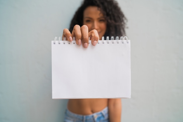 Young afro woman holding blank paper.
