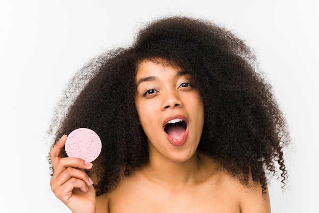 Young afro woman holding a facial disk isolated impressed holding copy space on palm.