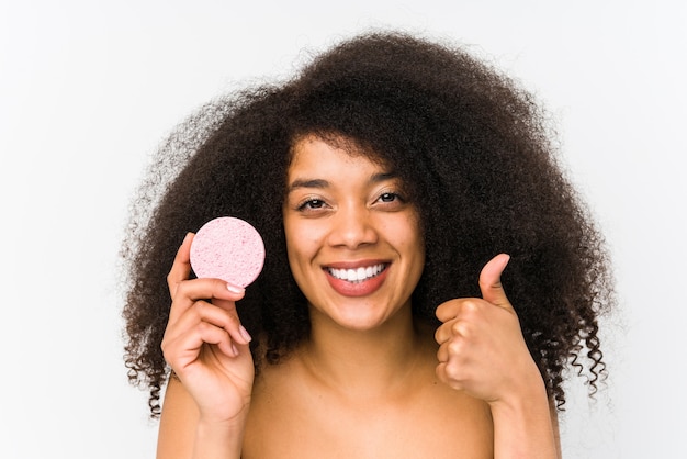 Young afro woman holding a facial disk smiling and raising thumb up