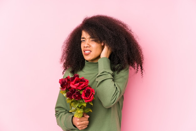 Молодая афро женщина, держащая розы изолированы Молодая афро женщина, держащая розы, открывая уши руками.