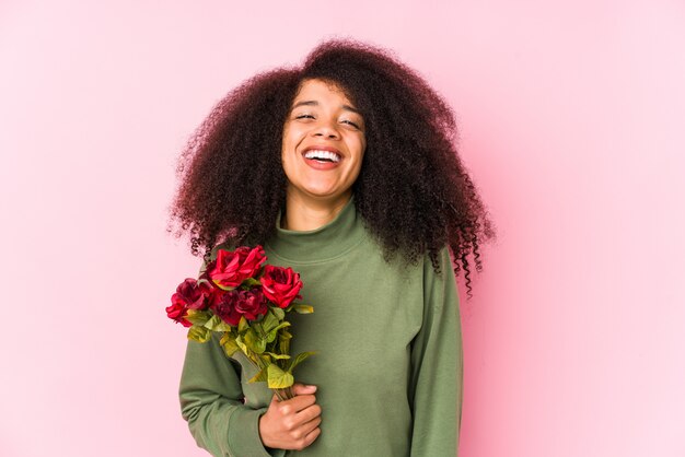 Young afro woman holding a roses isolated Young afro woman holding a roseslaughing and having fun.