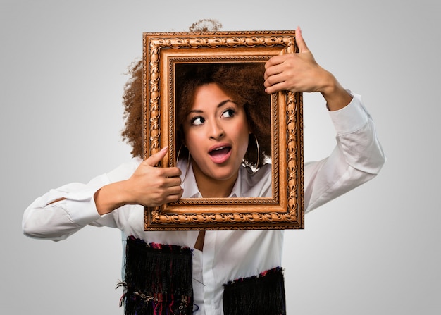 Young afro woman holding a vintage frame