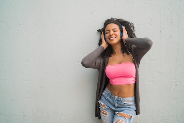 Young afro woman listening to music with headphones.