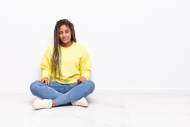 Giovane donna afro che sembra felice e amichevole, sorridente e ammiccante