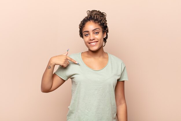 Young afro woman looking happy, proud and surprised isolated