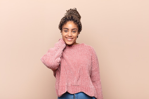 Young afro woman looking shocked and surprised with mouth wide open