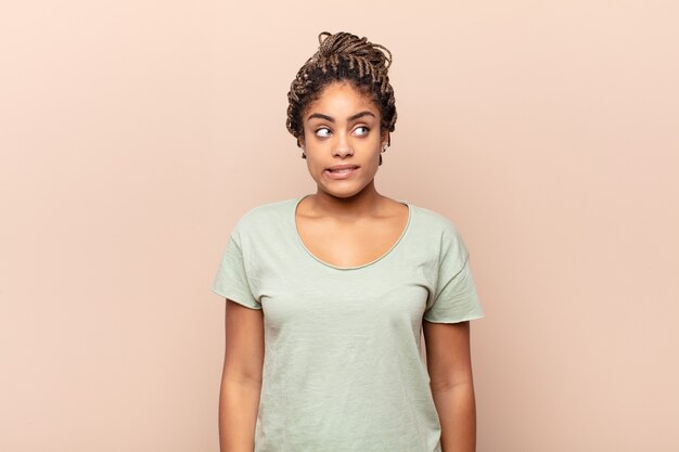 Young afro woman looking worried, stressed, anxious and scared, panicking and clenching teeth