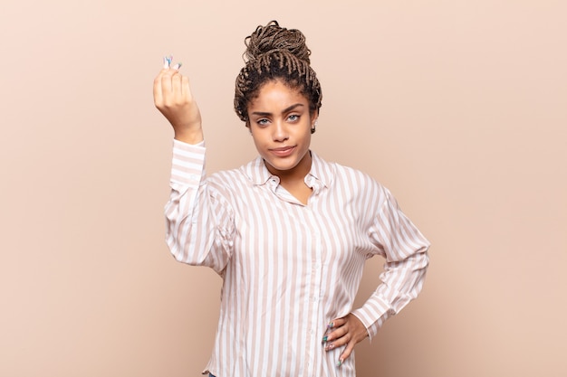 Young afro woman making capice or money gesture, telling you to pay your debts!