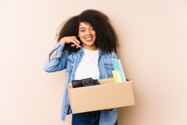 Young afro woman moving home isolated Young afro woman showing a mobile phone call gesture with fingers.