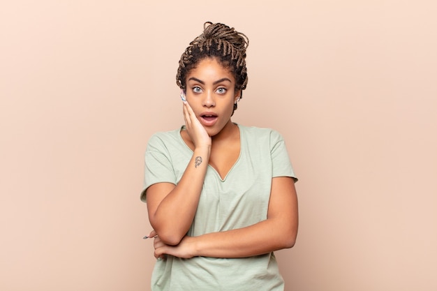 Young afro woman open-mouthed in shock and disbelief