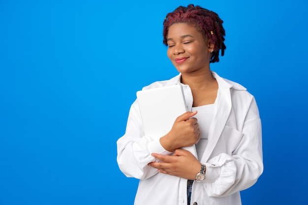 Young afro woman rolls up her sleeve against blue background