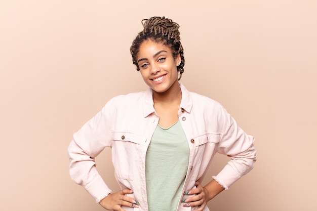 Young afro woman smiling cheerfully and casually with a positive, happy, confident and relaxed expression