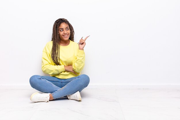 Young afro woman smiling happily and looking sideways