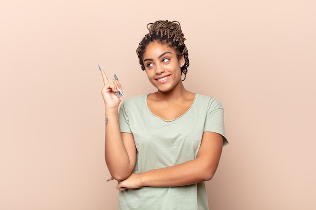 Young afro woman smiling happily and looking sideways