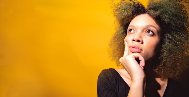 Foto giovane donna afro che pensa su sfondo giallo